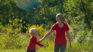 Genç bir kadın ve küçük oğlu yavaş çekim eğlenceli bir çimenlikte var