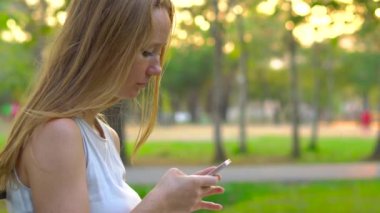 Steadycam atış bir cep telefonu kullanan bir parkta oturan genç bir kadın