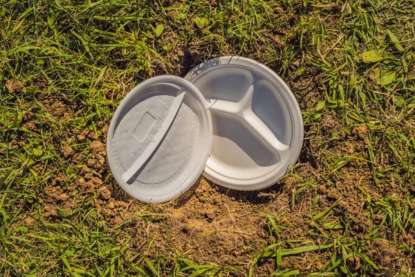 Le garçon joue au recyclage. Il enterre des plats jetables en plastique et des plats biodégradables — Photo