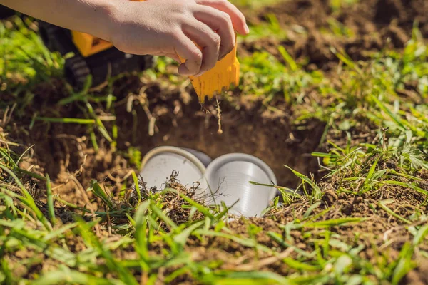 The boy plays recycling. He buries plastic disposable dishes and biodegradable dishes — Stock Photo, Image