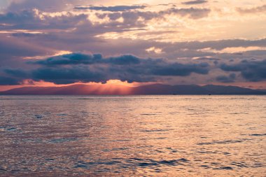 Denizin üzerinde güzel bir gün batımı, suda yansıması, gökyüzünde görkemli bulutlar