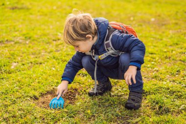 Çocuk geri dönüşüm çalıyor. Plastik tek kullanımlık tabakları ve ayrıştırılabilir tabakları gömüyor. Birkaç ay sonra, bulaşıkları kazıp çıkardı ve ayrıştırılabilir tabakların çözülmeye başladığını gördü.