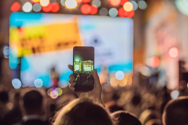 Use advanced mobile recording, fun concerts and beautiful lighting, Candid image of crowd at rock concert, Close up of recording video with smartphone, Enjoy the use of mobile photography