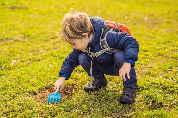 O rapaz joga reciclagem. Ele enterra pratos descartáveis de plástico e pratos biodegradáveis. Depois de alguns meses, ele desenterrou os pratos e viu que os pratos biodegradáveis começaram a se decompor e plástico fez — Fotografia de Stock