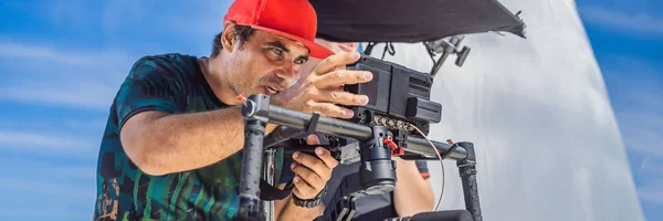 the production team on a commercial video shoot. Steadicam operator uses the 3-axis camera stabilizer and cinema-grade camera BANNER, LONG FORMAT