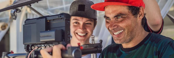 Il team di produzione per un servizio video commerciale. L'operatore Steadicam utilizza lo stabilizzatore della fotocamera a 3 assi e la telecamera di livello cinematografico BANNER, FORMATO LUNGO — Foto Stock