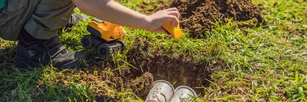 The boy plays recycling. He buries plastic disposable dishes and biodegradable dishes BANNER, LONG FORMAT — Stock Photo, Image