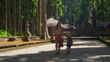 Genç bir kadın ve oğlu Bali Adası, Endonezya Sangeh maymun orman içinde yürüyüş Slowmotion atış.