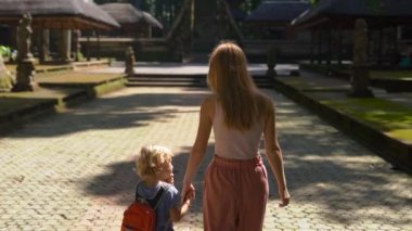 Genç bir kadın ve oğlu Bali Adası, Endonezya Sangeh maymun orman içinde yürüyüş Slowmotion atış.