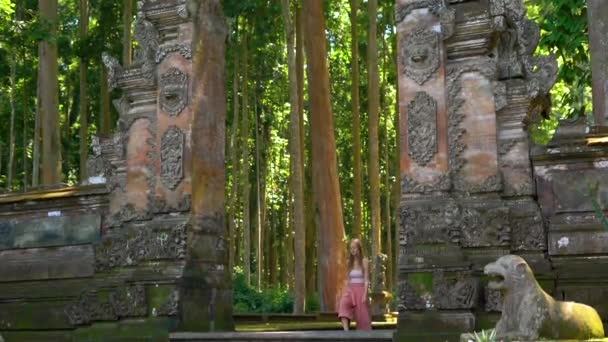 Toma en cámara lenta de una joven mujer caminando por las puertas del bosque de monos Sangeh, en la isla de Bali, Indonesia . — Vídeos de Stock