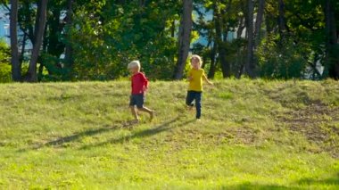 İki küçük çocuğu birlikte elele tepenin üst kısmından koşma Slowmotion vurdu. Dostluk kavramı. Destek kavramı
