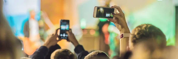 Use advanced mobile recording, fun concerts and beautiful lighting, Candid image of crowd at rock concert, Close up of recording video with smartphone, Enjoy the use of mobile photography BANNER, LONG