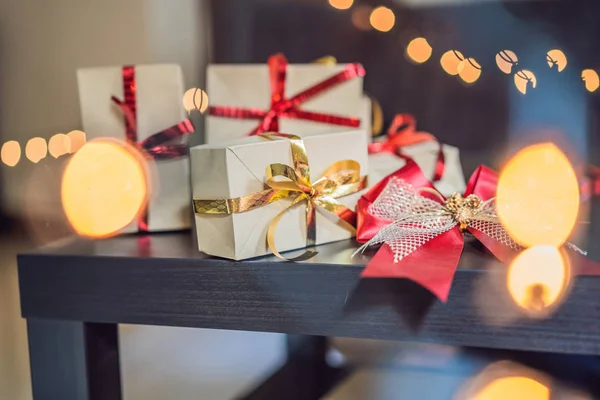 Presents wrapped in craft paper with red and gold ribbons for Christmas.