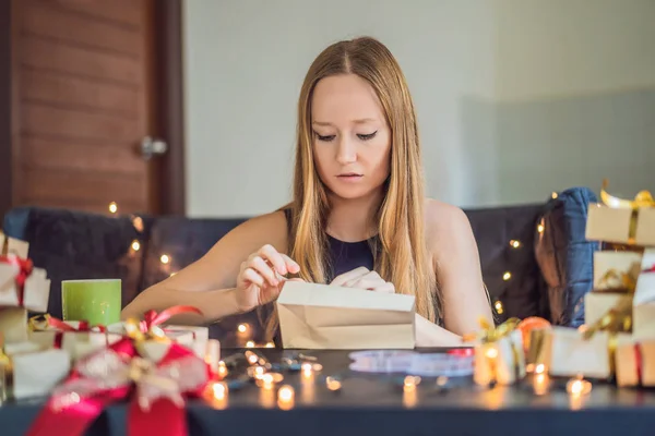 年轻女子包装圣诞礼物在工艺纸在桌上 — 图库照片