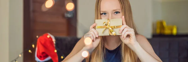 Young woman posing with present wrapped in craft paper for Christmas