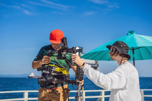 Operador Steadicam y su asistente preparan cámara y estabilizador-cardán de 3 ejes para un rodaje comercial —  Fotos de Stock