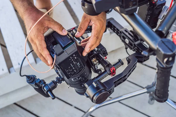 Operador Steadicam y su asistente preparan cámara y estabilizador-cardán de 3 ejes para un rodaje comercial — Foto de Stock