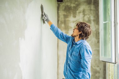 Genç ana duvarda beyaz macun uygulama ve gündüzleri ev tadilatı Oda macun bıçak ile bulaşması.