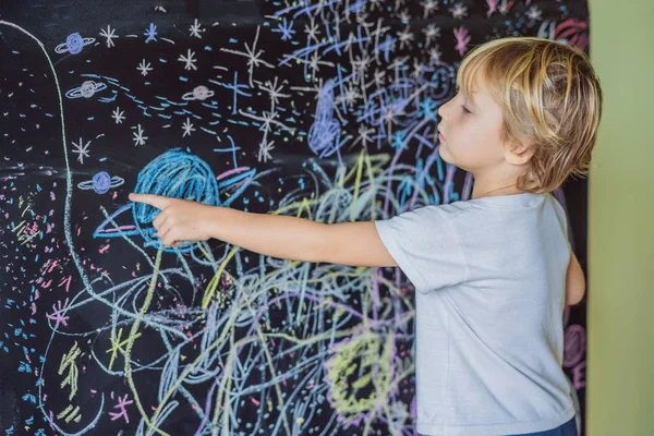 Niño apuntando al espacio, planetas y estrellas en la pared — Foto de Stock