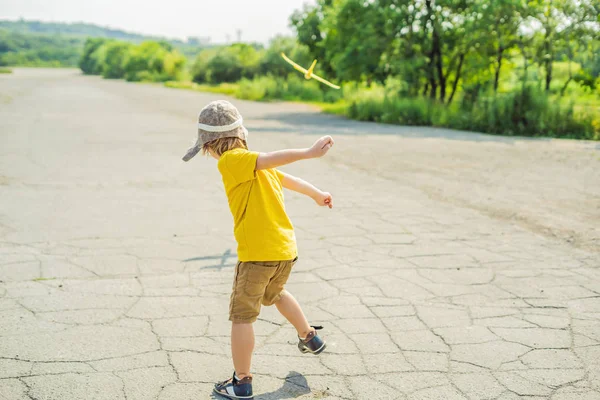 Gelukkig kind spelen met speelgoed vliegtuig tegen oude baan achtergrond. Reizen met kids concept — Stockfoto