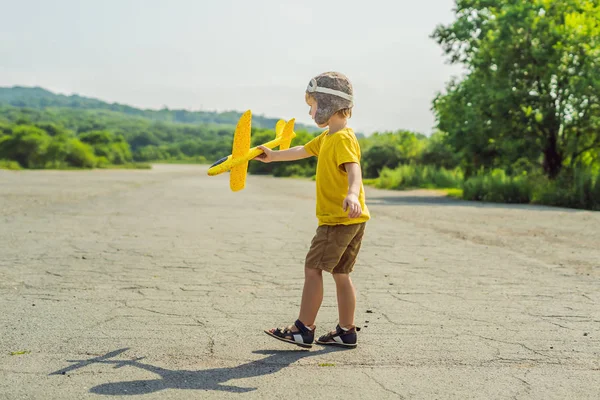 Gelukkig kind spelen met speelgoed vliegtuig tegen oude baan achtergrond. Reizen met kids concept — Stockfoto