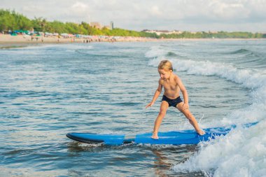 Küçük çocuk acemi kurulu tropik sahilde sörf.