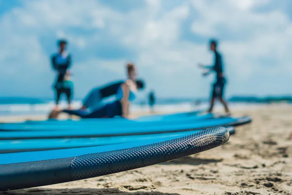 Blue surfboards in sand on beach with people in background.