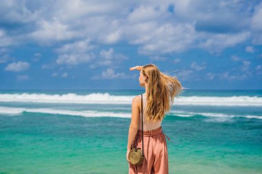 Genç kadın gezgin rahatlatıcı Melasti plaj turkuaz su, Bali Adası, Endonezya ile.