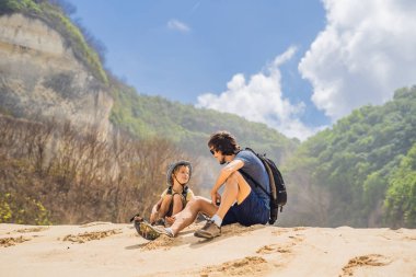 Baba ve oğul Melasti Beach, Bali Adası, Endonezya kumsalda oturuyor. 