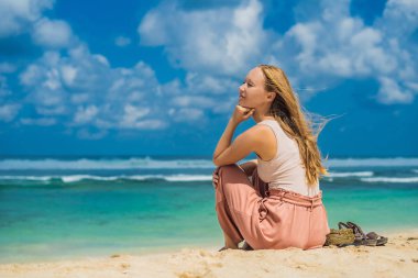Turkuaz deniz, Bali Adası, Endonezya tarafından kum Melasti plajındaki oturan genç kadın.