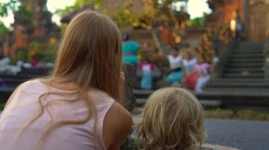 Bali, Endonezya - olabilir. Genç bir kadın ve küçük oğlu Saraswati tapınağın kızlar grup geleneksel Balinese öğretim kadın öğretmen izlerken Ubud köyünde 16 Slowmotion atış