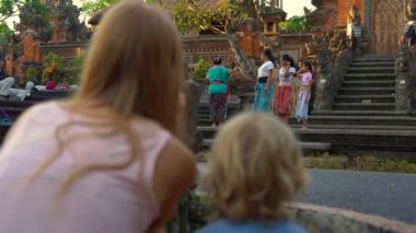 Bali, Endonezya - olabilir. Genç bir kadın ve küçük oğlu Saraswati tapınağın kızlar grup geleneksel Balinese öğretim kadın öğretmen izlerken Ubud köyünde 16 Slowmotion atış