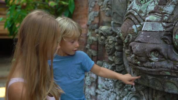 Slowmotion strzał z piękną młodą kobietę i jej synka, zwiedzanie Pałacu Królewskiego Puri Saren w Ubud village na wyspie Bali. Podróż do Indonezji koncepcja. Podróż z dziećmi koncepcja — Wideo stockowe
