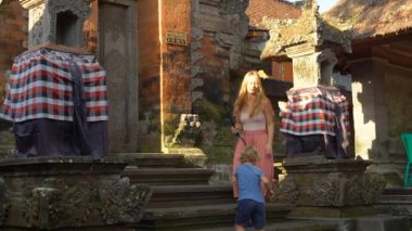 Güzel bir genç kadın ve küçük oğlu Slowmotion atış Balinese Tapınağı merdivenlerde bir eylem kamera ile bir selfie olun. Endonezya kavramı için seyahat. Çocuk kavramı ile seyahat