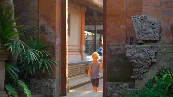 Slowmotion πλάνο του μια όμορφη νεαρή γυναίκα και τον μικρό γιο που επισκέπτονται το Puri Saren βασιλικό παλάτι στο Ubud χωριό στο νησί Μπαλί. Ταξίδι στην Ινδονησία έννοια. Ταξίδια με παιδιά — Αρχείο Βίντεο