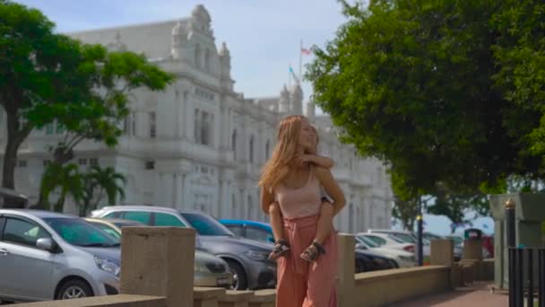 Filmagem em câmera lenta de uma jovem mulher e seu filhinho se divertindo em uma praça em frente a uma Prefeitura de Penang, Malásia — Vídeo de Stock