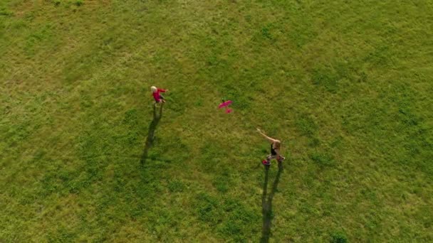 Luftaufnahme einer jungen Frau und ihres kleinen Sohnes beim Spielen mit einem Plastikflugzeug in einem Park — Stockvideo