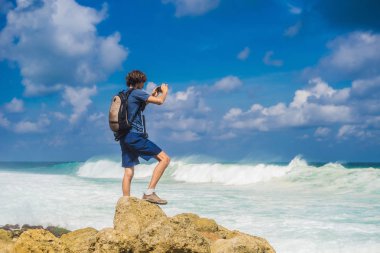 Alarak resmi smartphone turkuaz su, Melasti Beach, Bali Adası, Endonezya için genç adam.