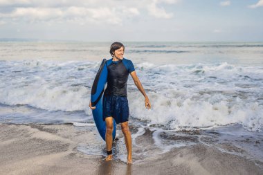 Su plajda sörf tahtası ayakta olan yakışıklı adam.