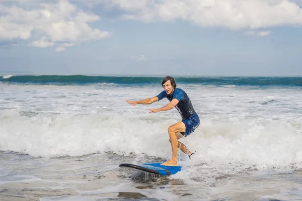 Young man surfing on sea water on Bali island.