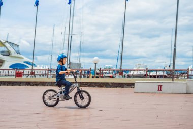 Mutlu çocuk çocuk eğleniyor bir bisiklet ile Yat Kulübü yakınındaki güzel gün. Etkin alt giyen Bisiklet kask