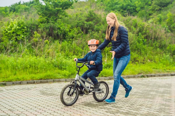 Máma učí syna jezdit na kole v parku — Stock fotografie