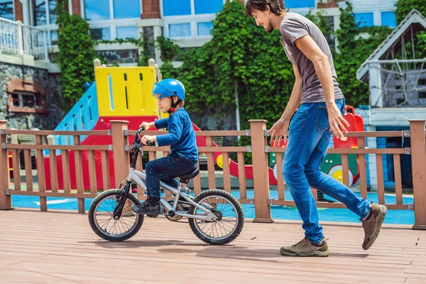 Папа учит сына кататься на велосипеде в парке — стоковое фото