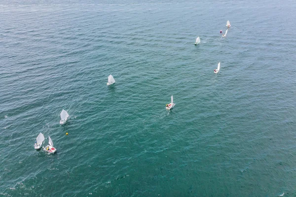 Luchtfoto drone foto van jonge tieners op kleine zeilboten concurreren in de regatta op mediterrane smaragdgroene zee — Stockfoto