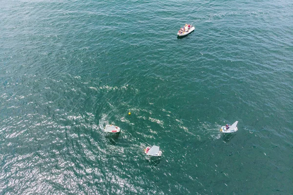Аэрофоторобот молодых подростков на небольших парусных лодках, участвующих в регате у Средиземного изумрудного моря — стоковое фото