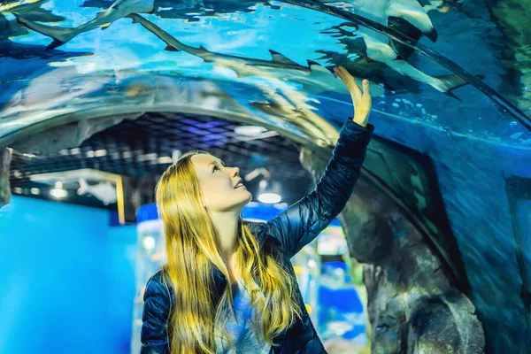 Een jonge vrouw kijkt naar vis in een tunnel in het oceanarium — Stockfoto