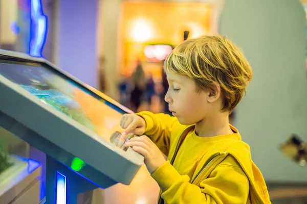 Der Junge in der gelben Jacke bedient sich eines Touchscreens — Stockfoto