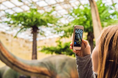 Cep telefonu ve dinozor Sergisi alarak fotoğraf kullanan kadın Close-up.