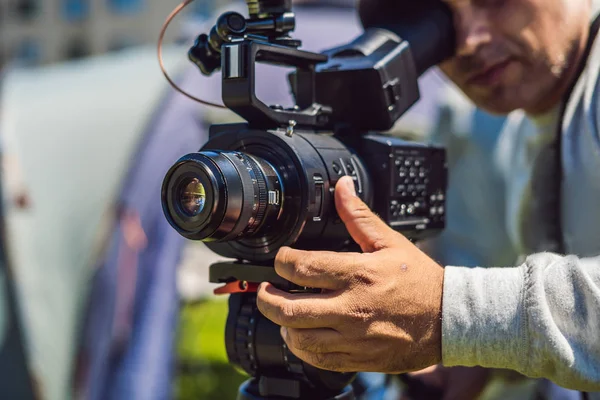 Un caméraman professionnel prépare une caméra et un trépied avant de tirer — Photo