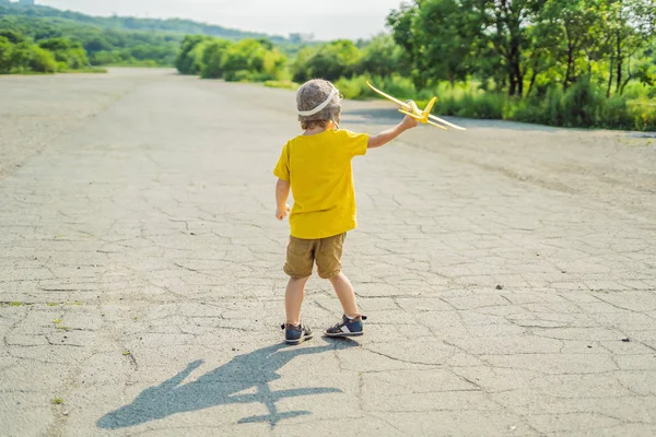 Gelukkig kind spelen met speelgoed vliegtuig tegen oude baan achtergrond. Reizen met kids concept — Stockfoto